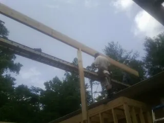 Carpenter setting a ridge beam over a new addition frame — Ice Dam Removal by Roofing Brothers in Rosemary Beach