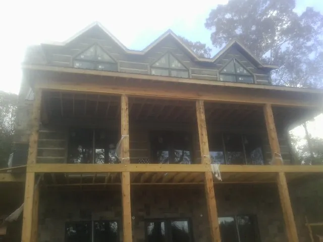Dormers and porch framing on a large log home under construction — Roof Coating work by our crew in Rosemary Beach