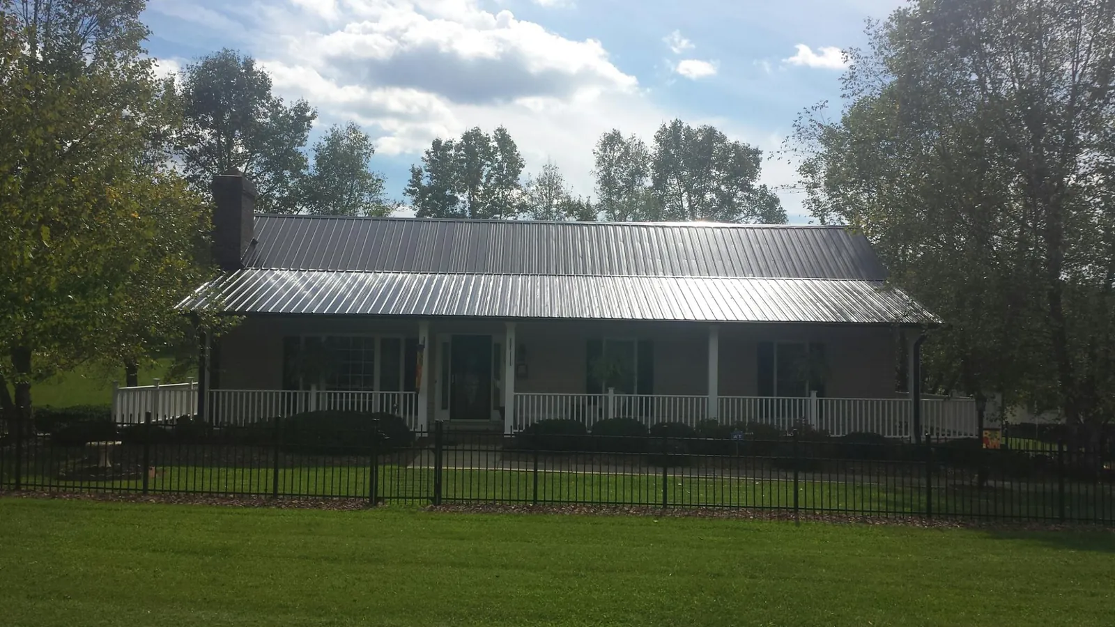 Gray metal roof on a brick ranch with a full width front porch — Gutter Guard Installation work by our crew in Rosemary Beach