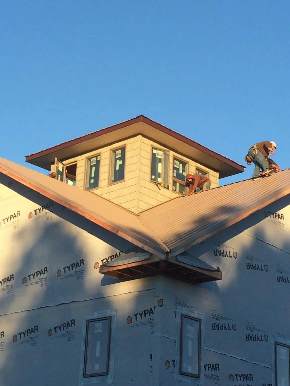 Roofers working around a rooftop cupola on a new metal roof at sunset — Roof Waterproofing in Rosemary Beach by Roofing Brothers